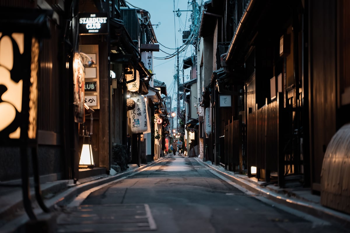 A lantern-lit alley in Gion at dusk with traditional wooden buildings