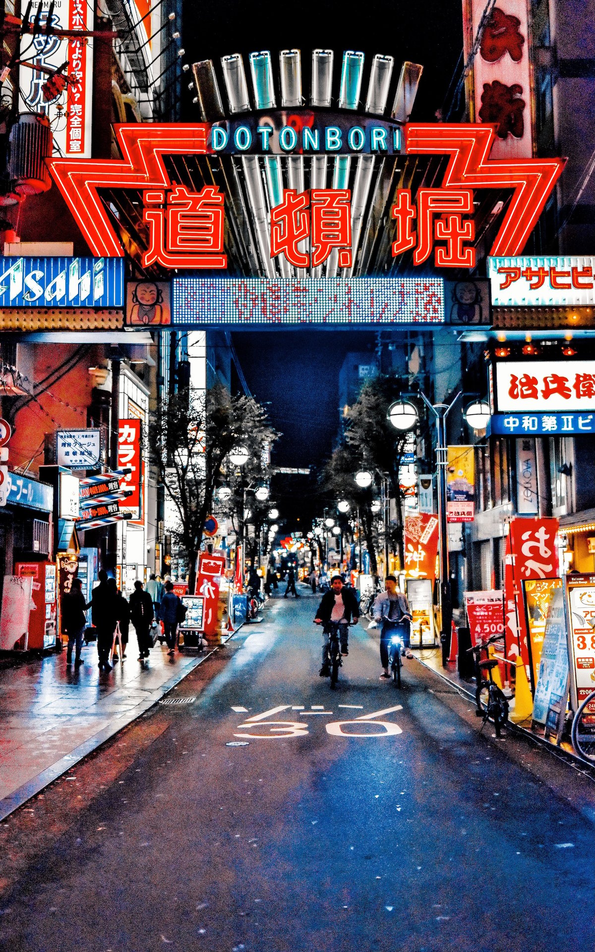 The illuminated Dotonbori sign over a street at night in Osaka