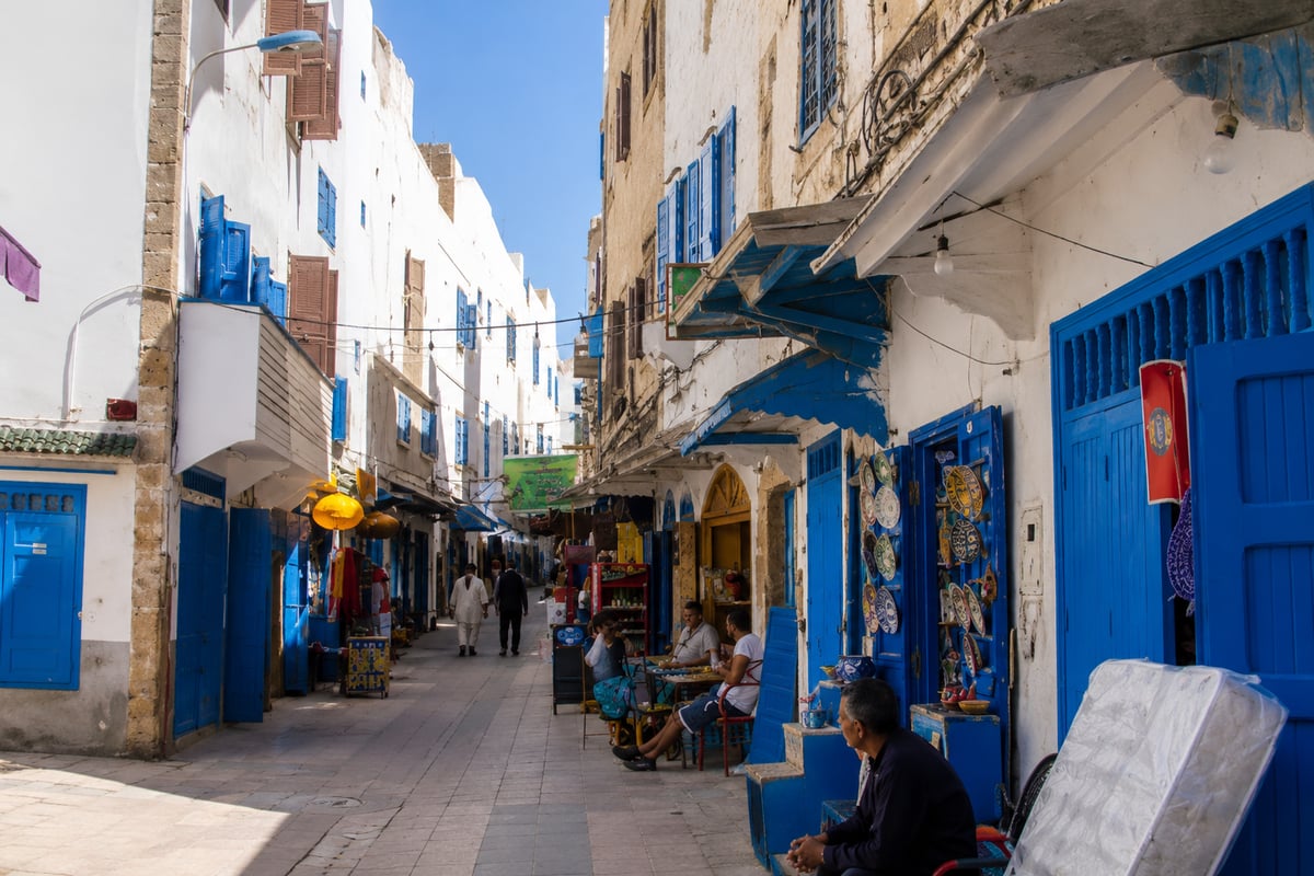 A quiet blue-and-white medina street in Essaouira, no clear faces