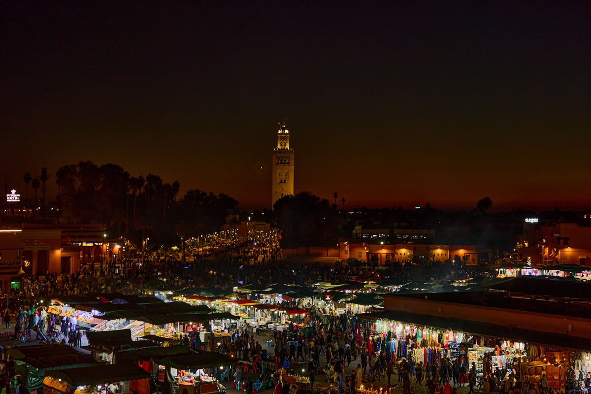 A row of numbered food stalls at Jemaa el-Fnaa at night, no clear faces