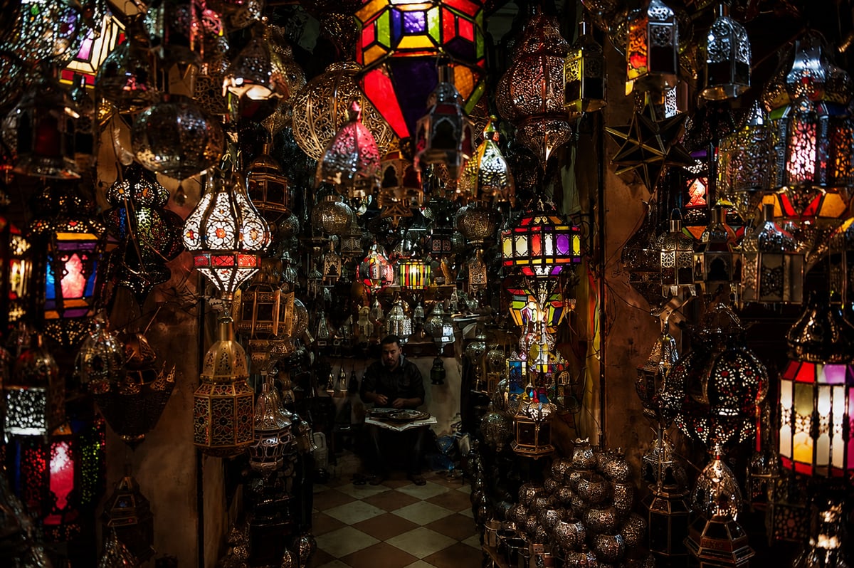 A quiet souk lane with lanterns and textiles in Marrakech, no clear faces