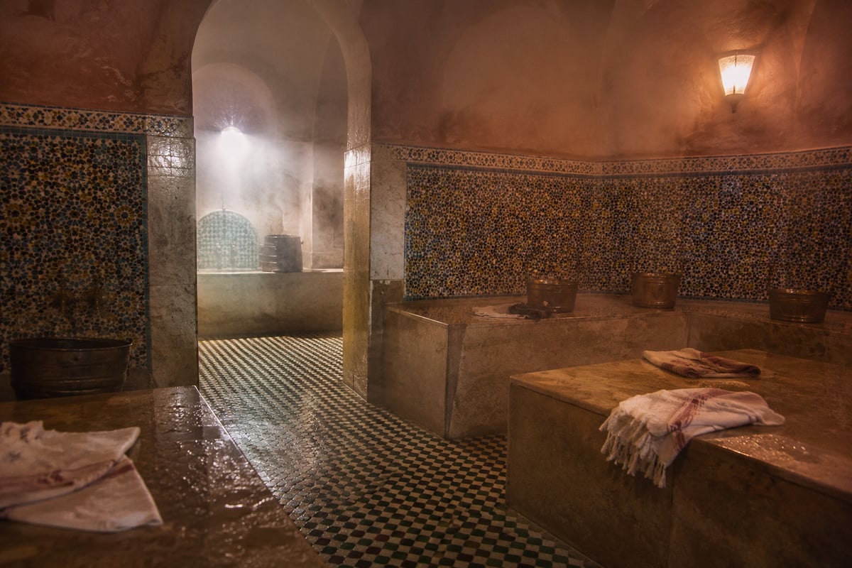 The tiled interior of a traditional hammam, steam and stone, no faces