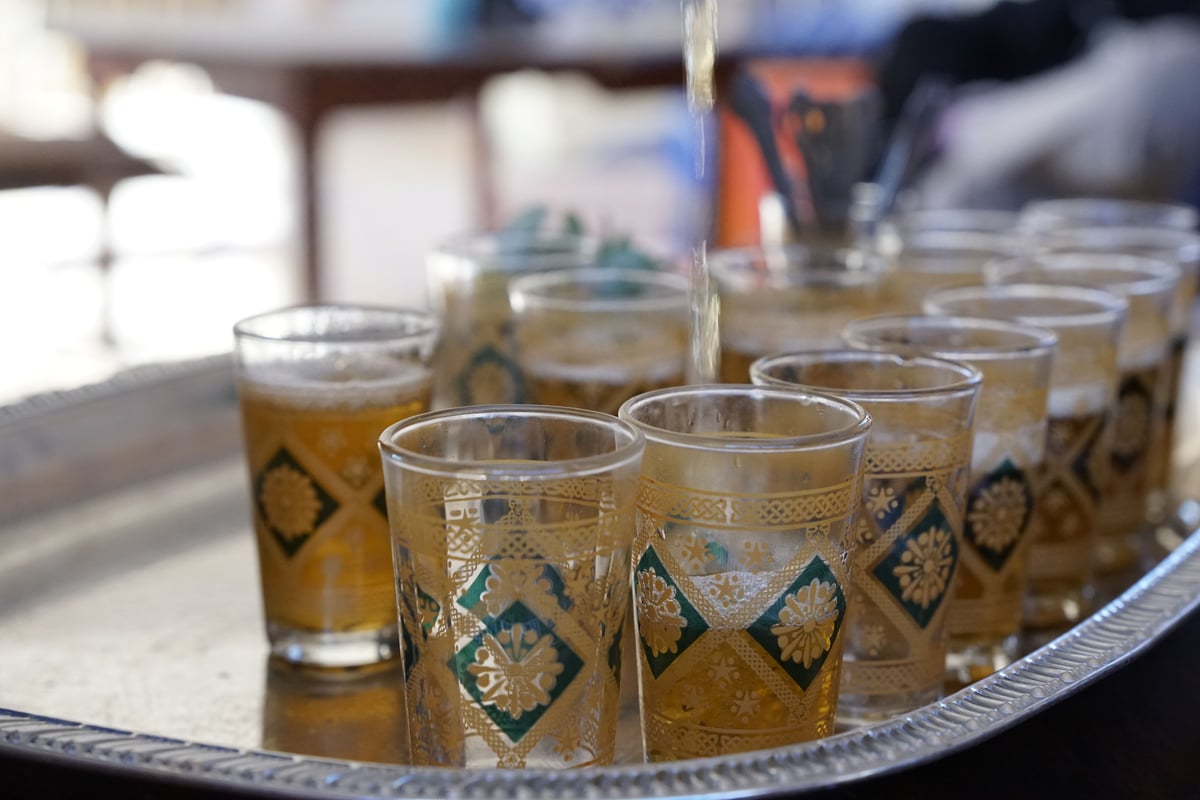 Mint tea being poured from height into a glass, no clear faces