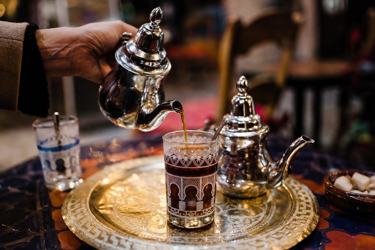 A silver teapot and glasses of mint tea on a tray, no faces