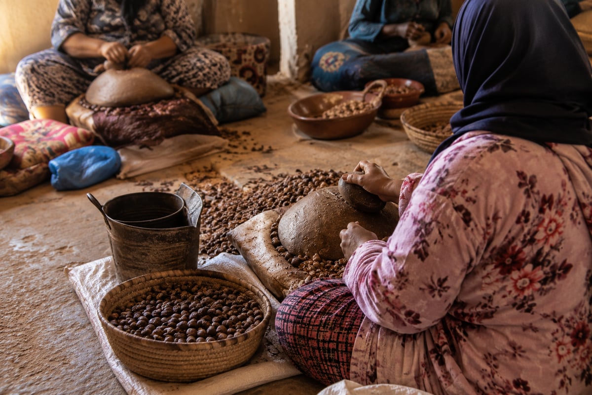 Women processing argan nuts by hand at a cooperative, no clear faces