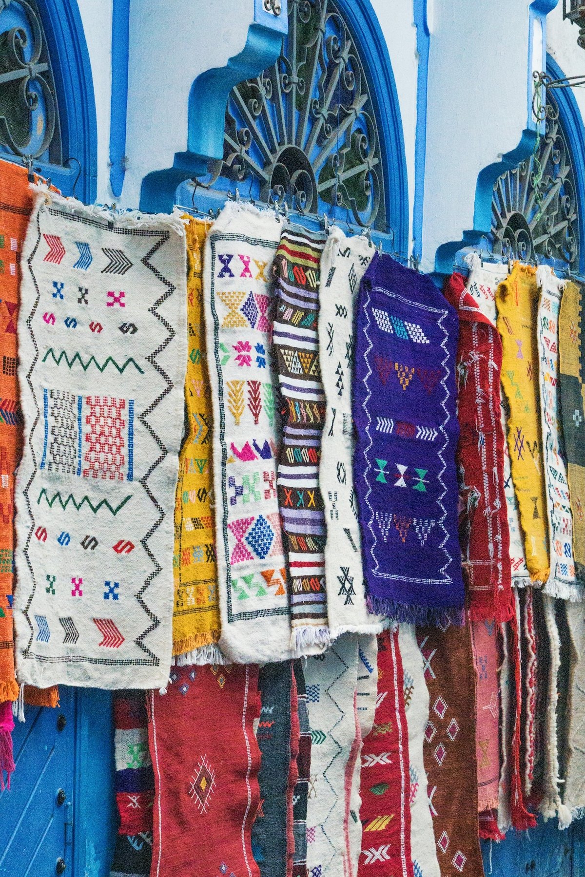 Stacked Moroccan rugs in rich colors and patterns, detail shot, no faces