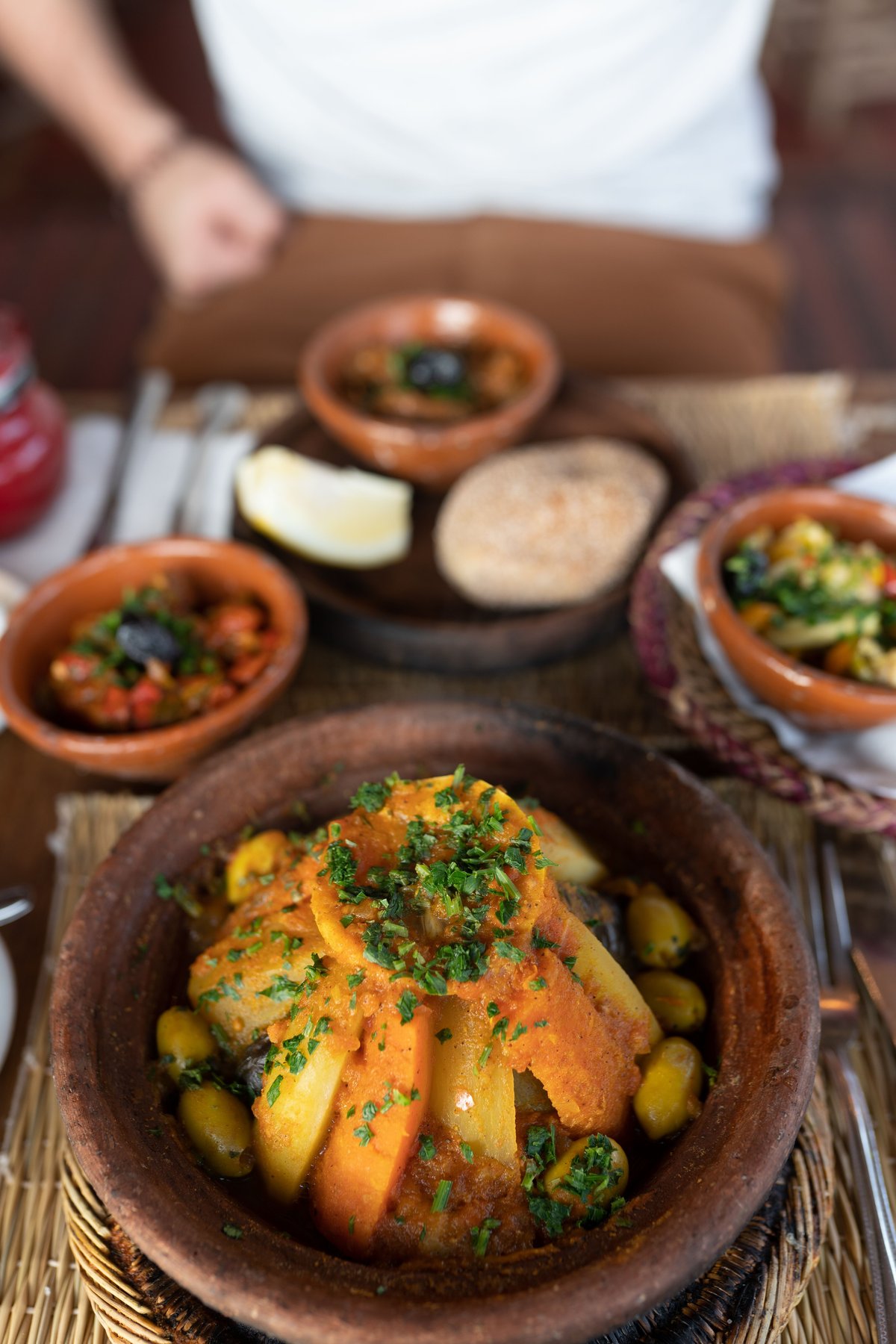 A finished Moroccan meal of tagine, salads and bread on a table, no faces