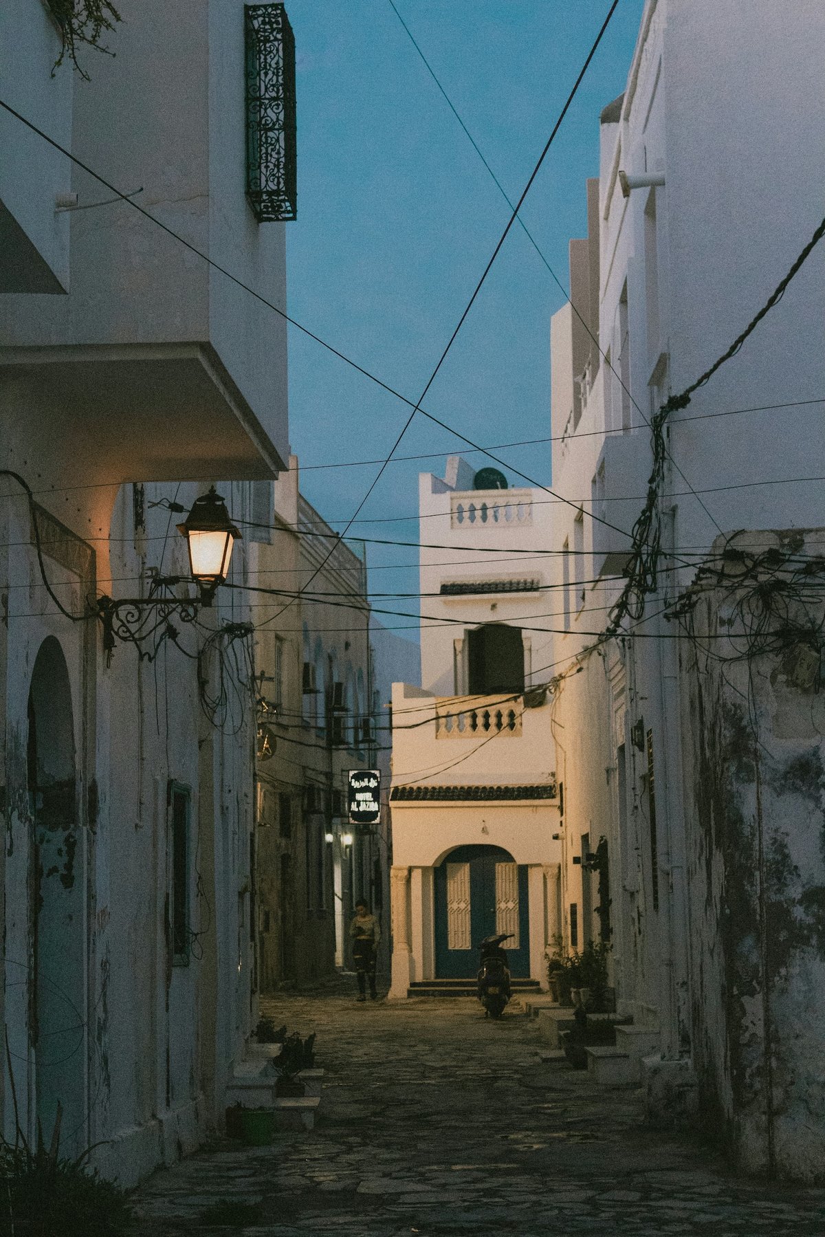 A Moroccan street at dusk during Ramadan with lanterns and gathering crowds, no clear faces