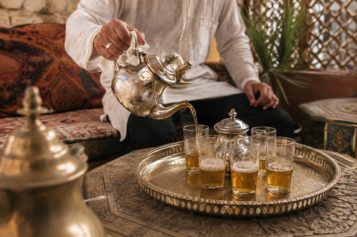 A Moroccan tea pouring ritual with glasses on a tray, no faces