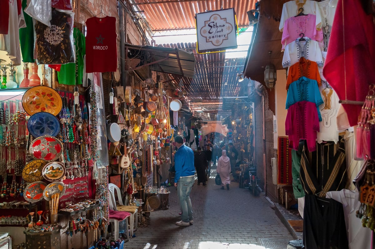 A busy medina lane with shopfronts and passers-by at a distance, no identifiable faces