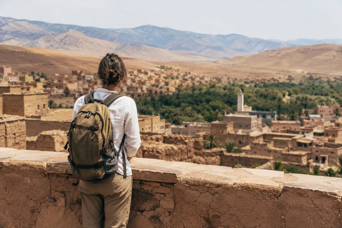 A traveler with a daypack looking over a Moroccan landscape, no clear face