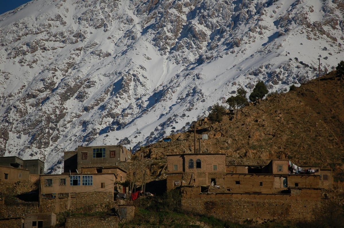 The snow-capped Atlas Mountains above a green valley, no faces