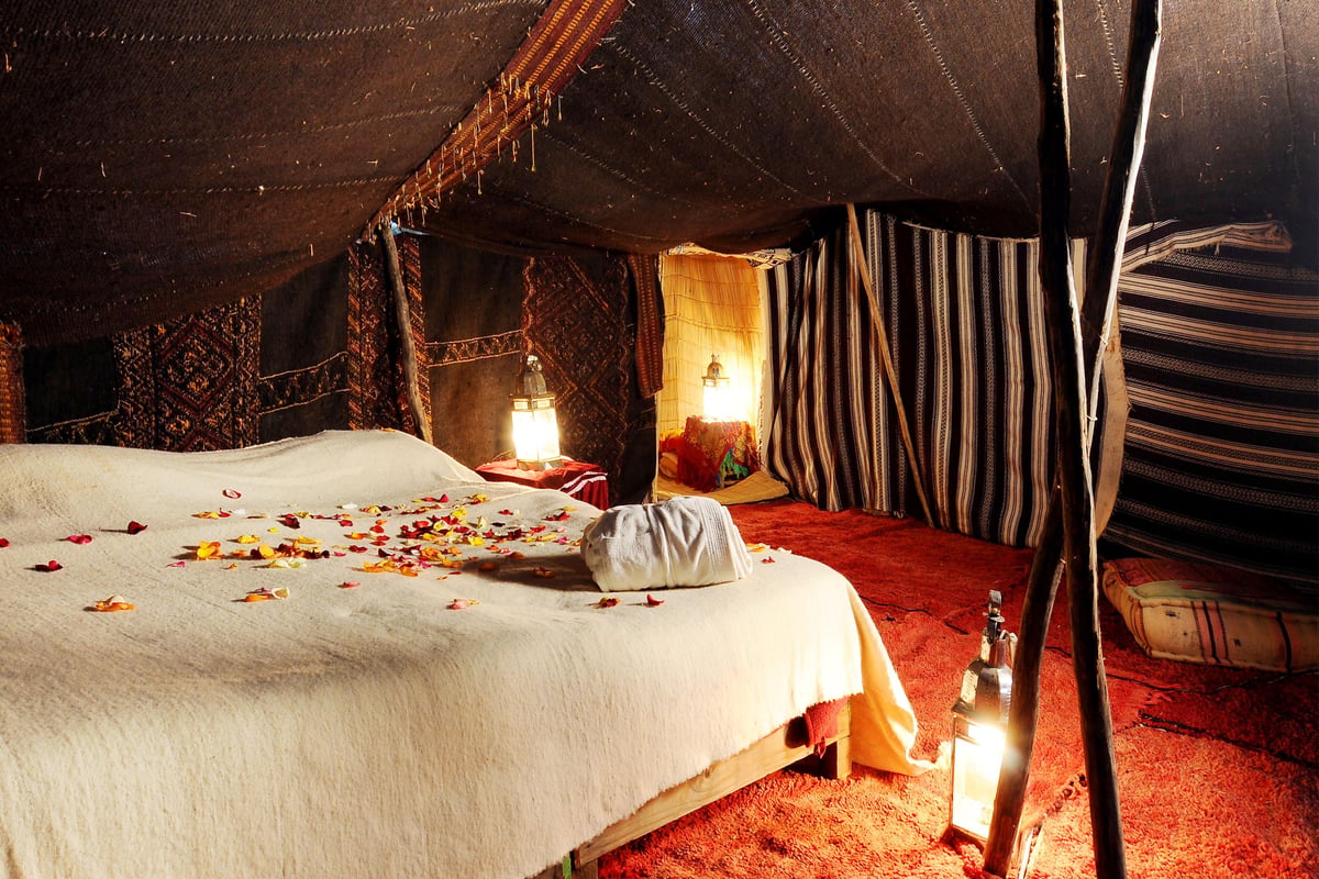 The interior of a comfortable desert tent with rugs and lanterns, no faces