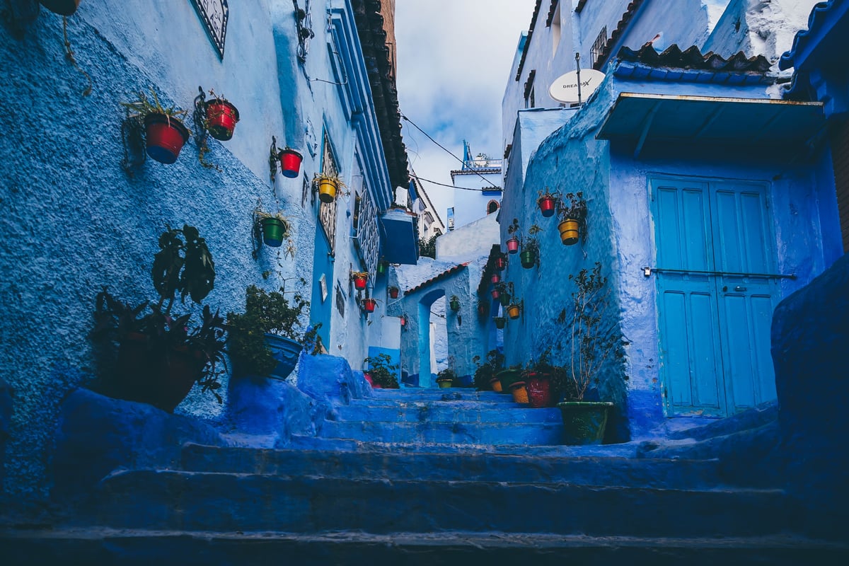 A classic blue-painted lane in Chefchaouen with steps and plants, no clear faces