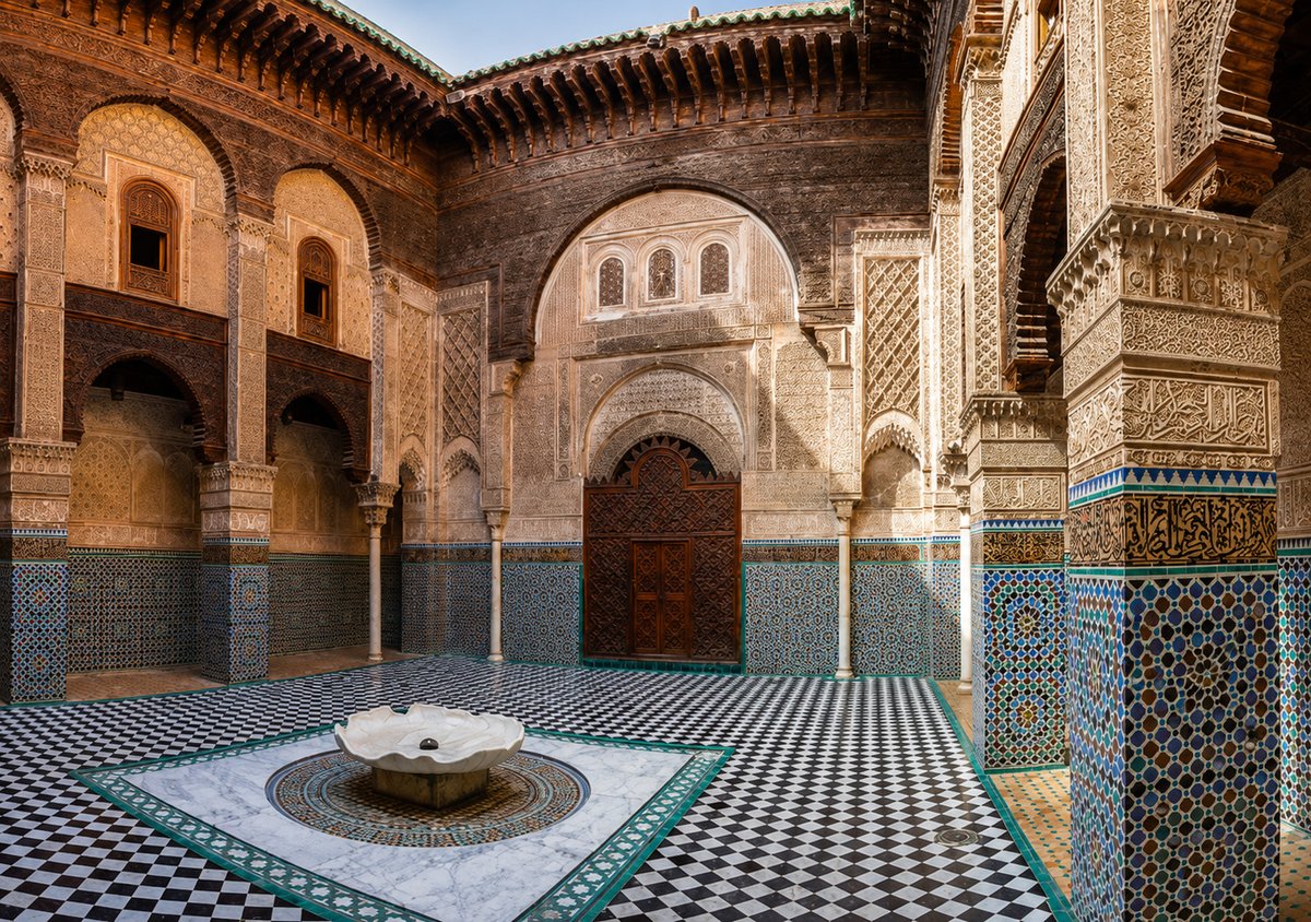 A madrasa courtyard in Fez with intricate tilework and carving, no faces