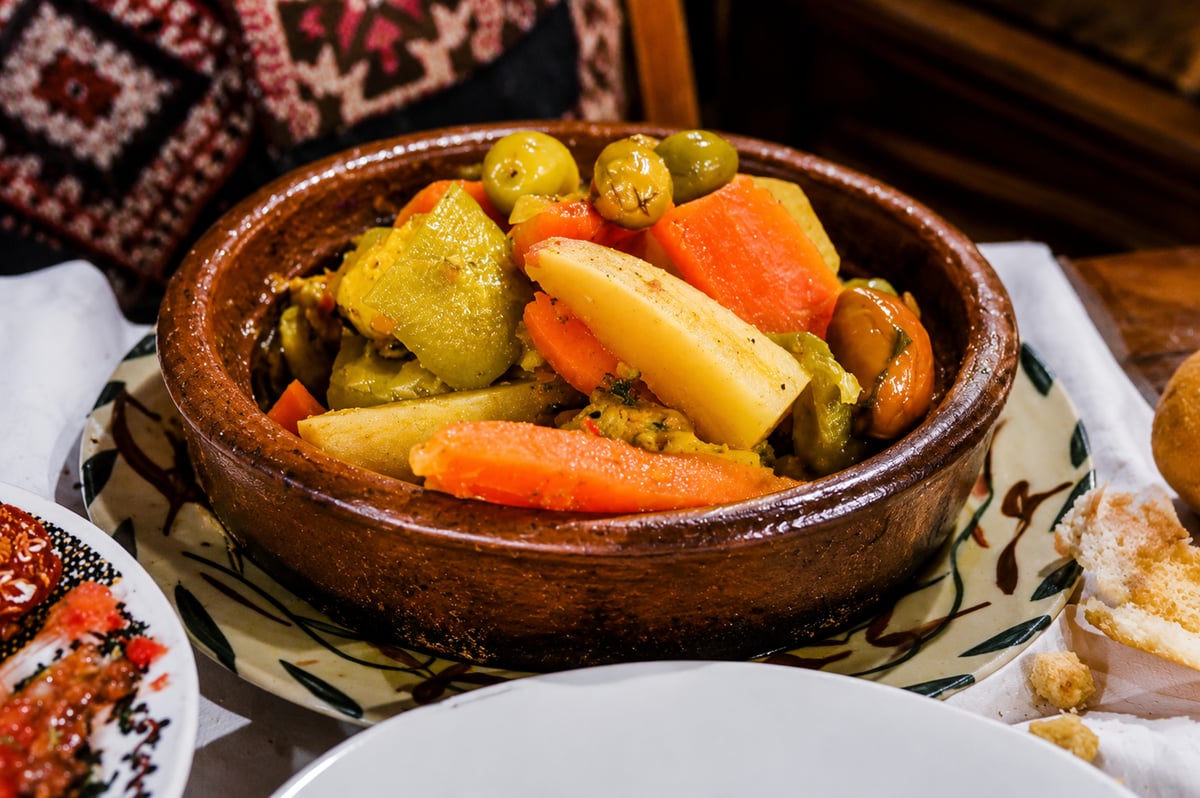 A colourful vegetable tagine and Moroccan salads on a table, no faces