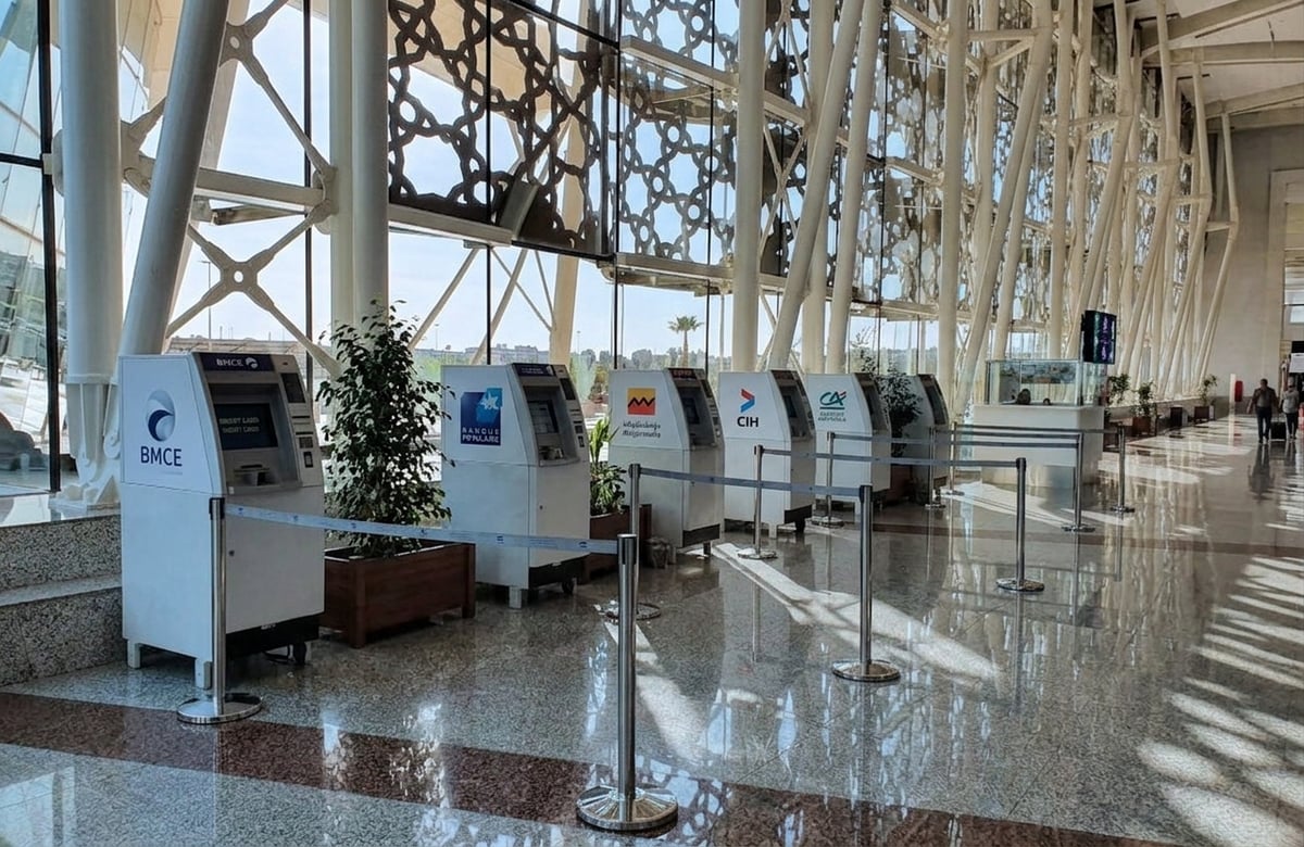 A row of bank ATMs in a Moroccan airport arrivals hall, no faces, no card details visible