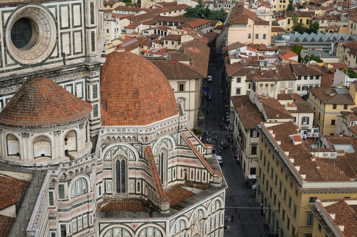Florence's cathedral dome seen from above, with the tiled rooftops of the compact historic centre around it