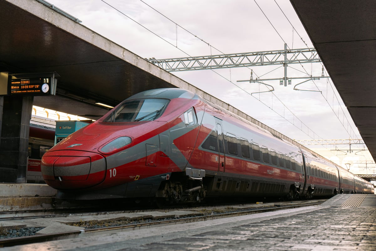 A red Trenitalia Frecciarossa high-speed train standing at a station platform