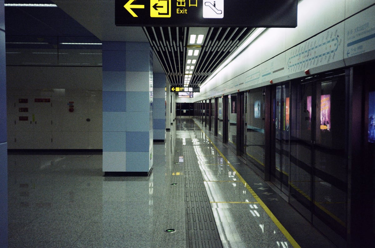 An empty metro platform with tiled columns and a yellow exit arrow overhead