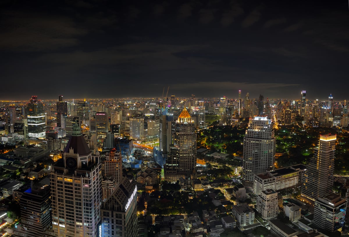 A bustling Bangkok market or a rooftop bar view over the skyline at dusk