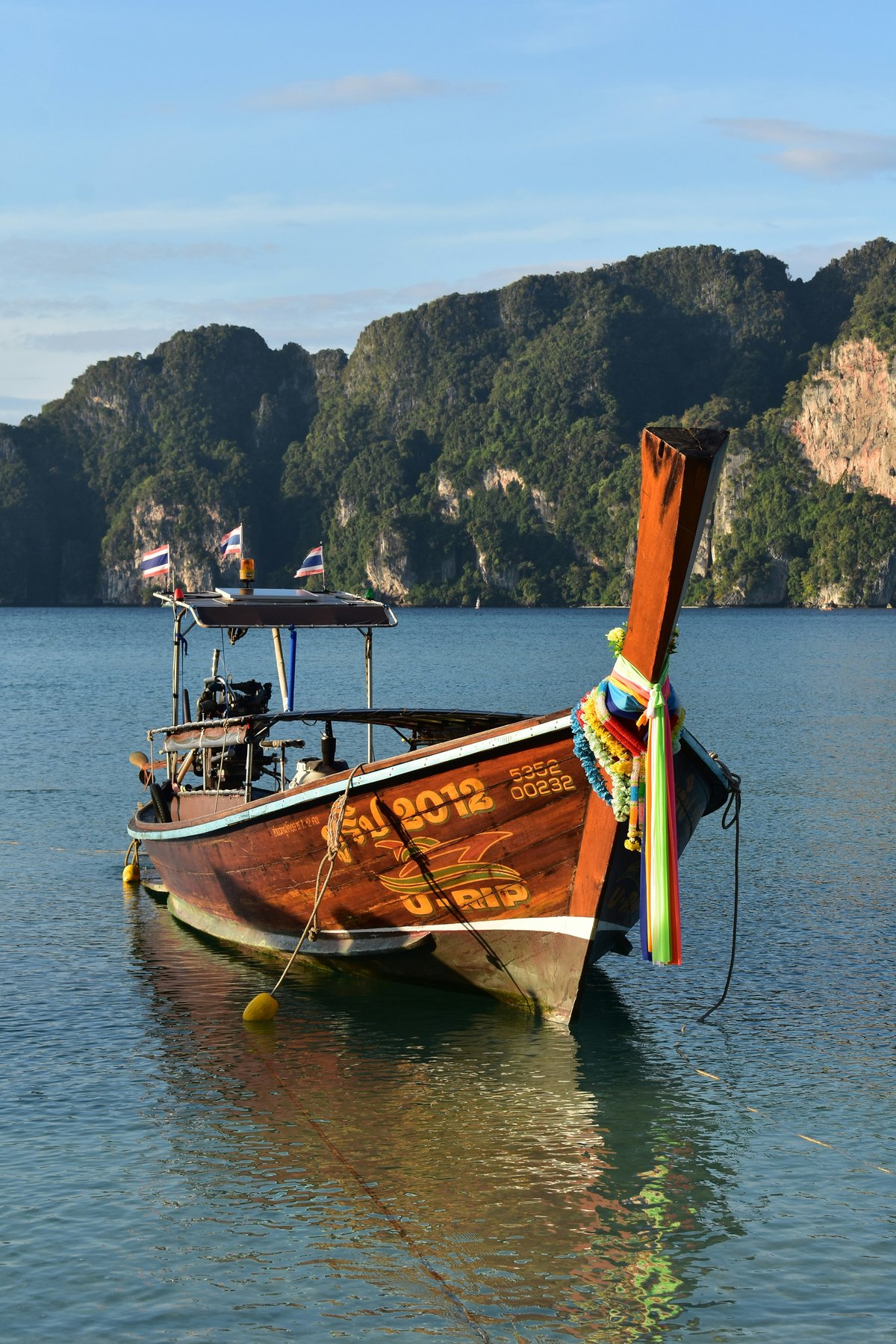 A longtail boat anchored off limestone karsts in clear water