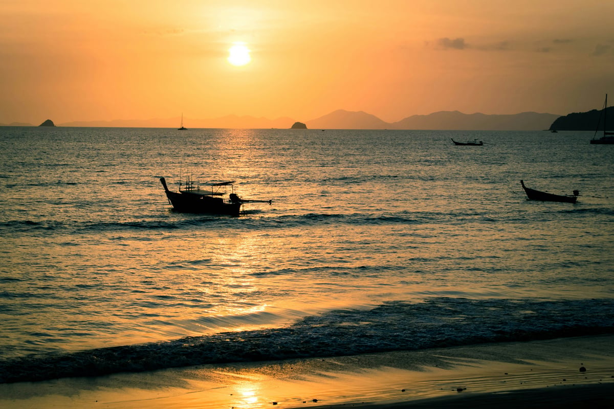 A dreamy Thai beach with clear shallow water and a longtail boat