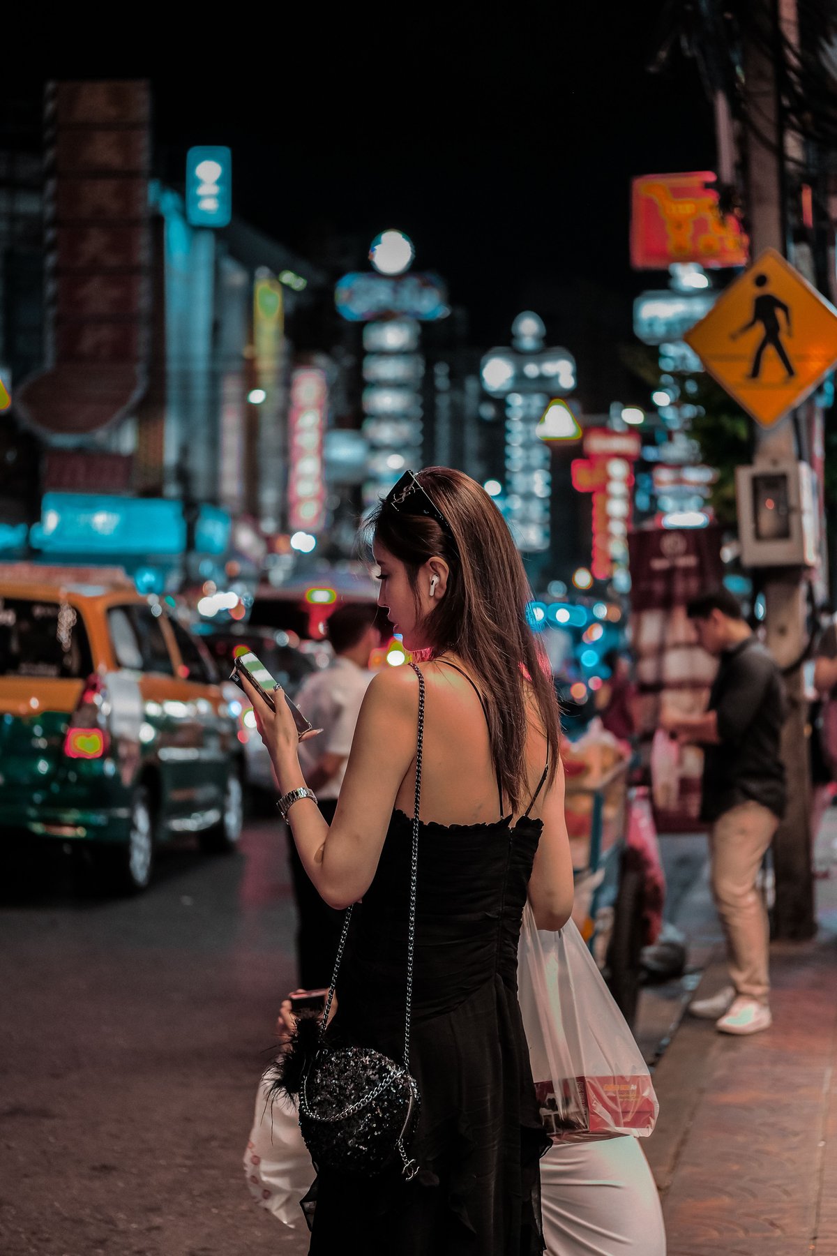 A traveler checking their phone with a Thai beach or Bangkok street behind