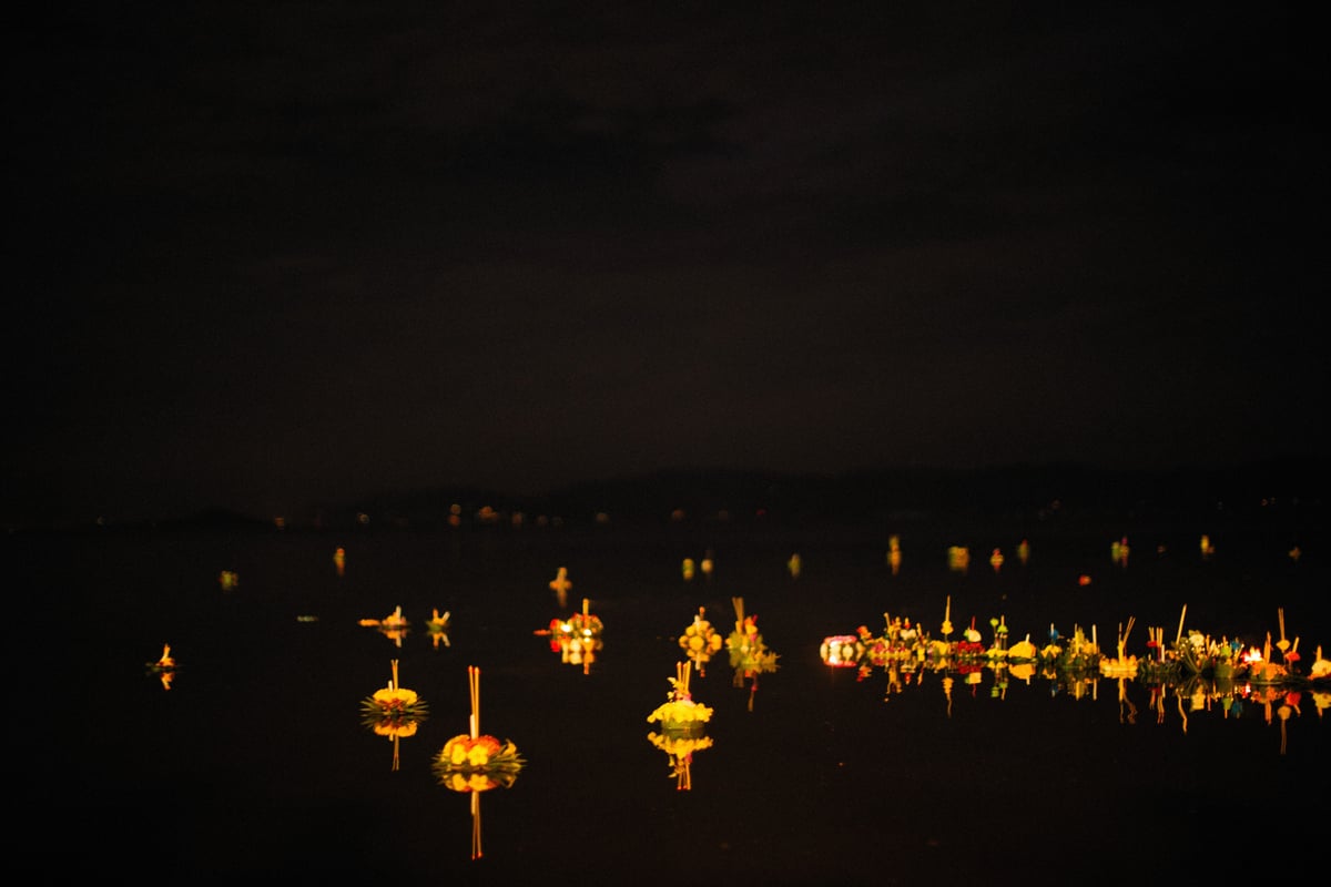 Candle-lit krathong floats on a river at Loy Krathong