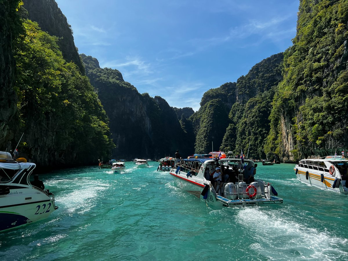A speedboat or ferry crossing turquoise water between Thai islands