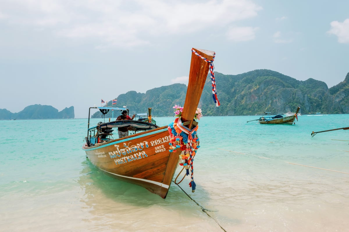 A longtail boat in a turquoise Phi Phi bay with cliffs