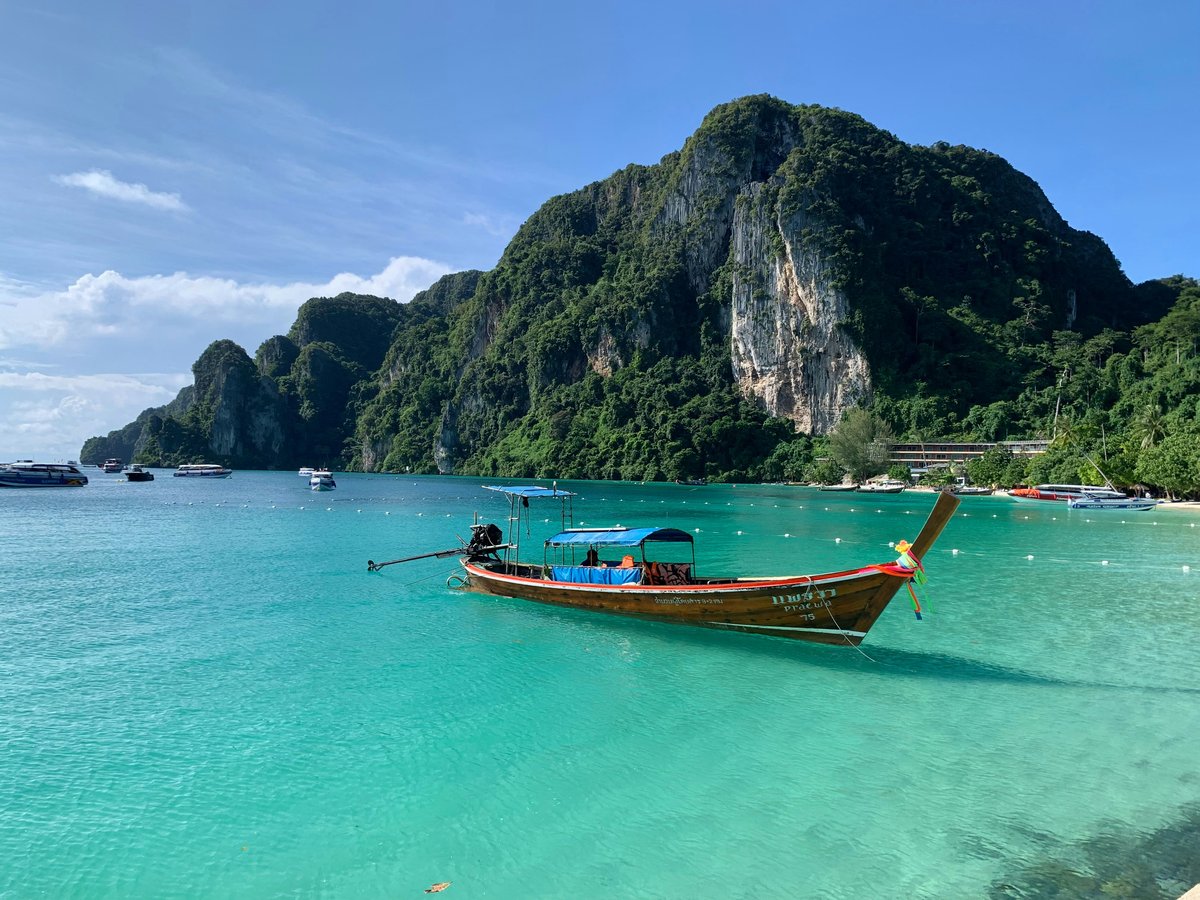 Railay's towering limestone cliffs over a turquoise beach with longtail boats