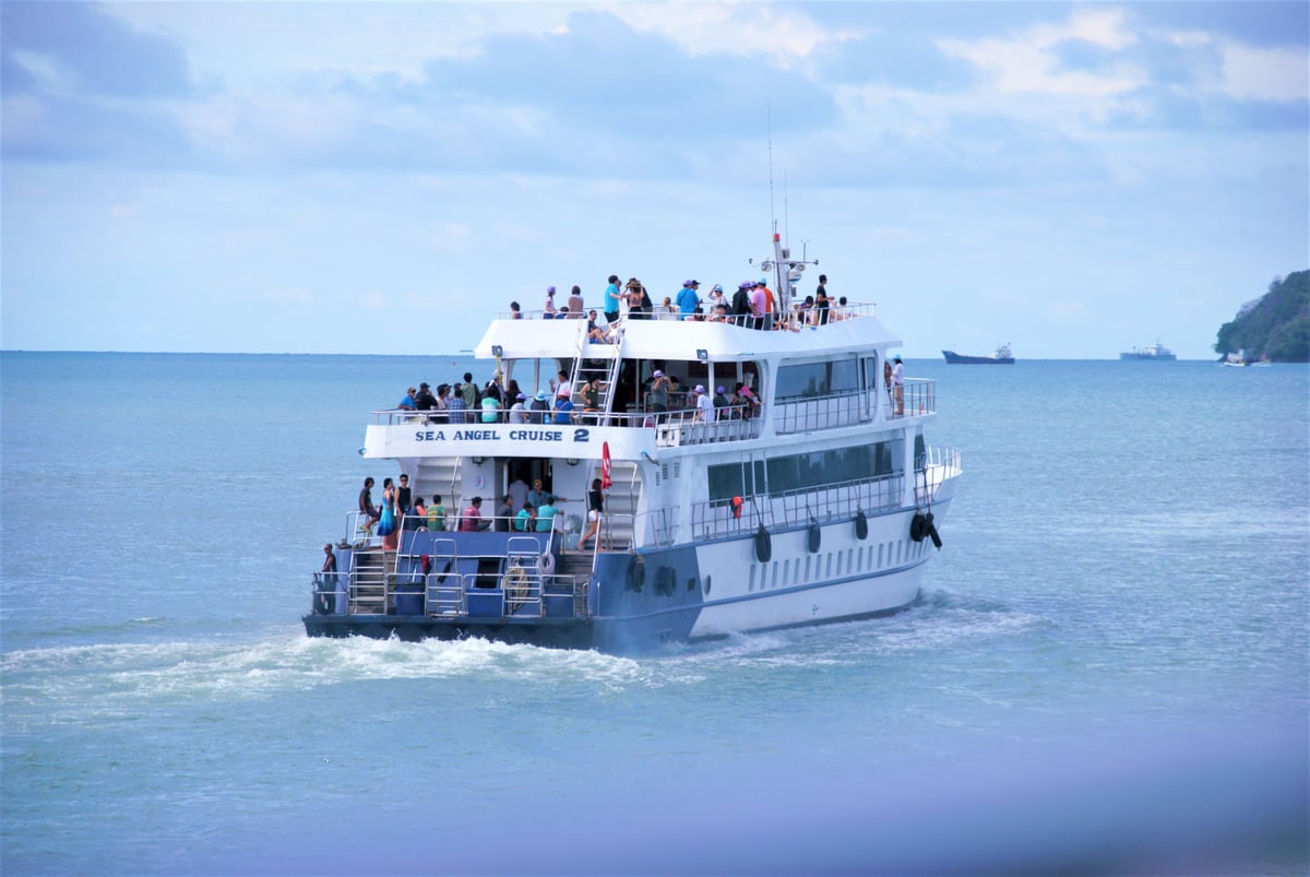 A passenger ferry crossing turquoise water toward a Thai island