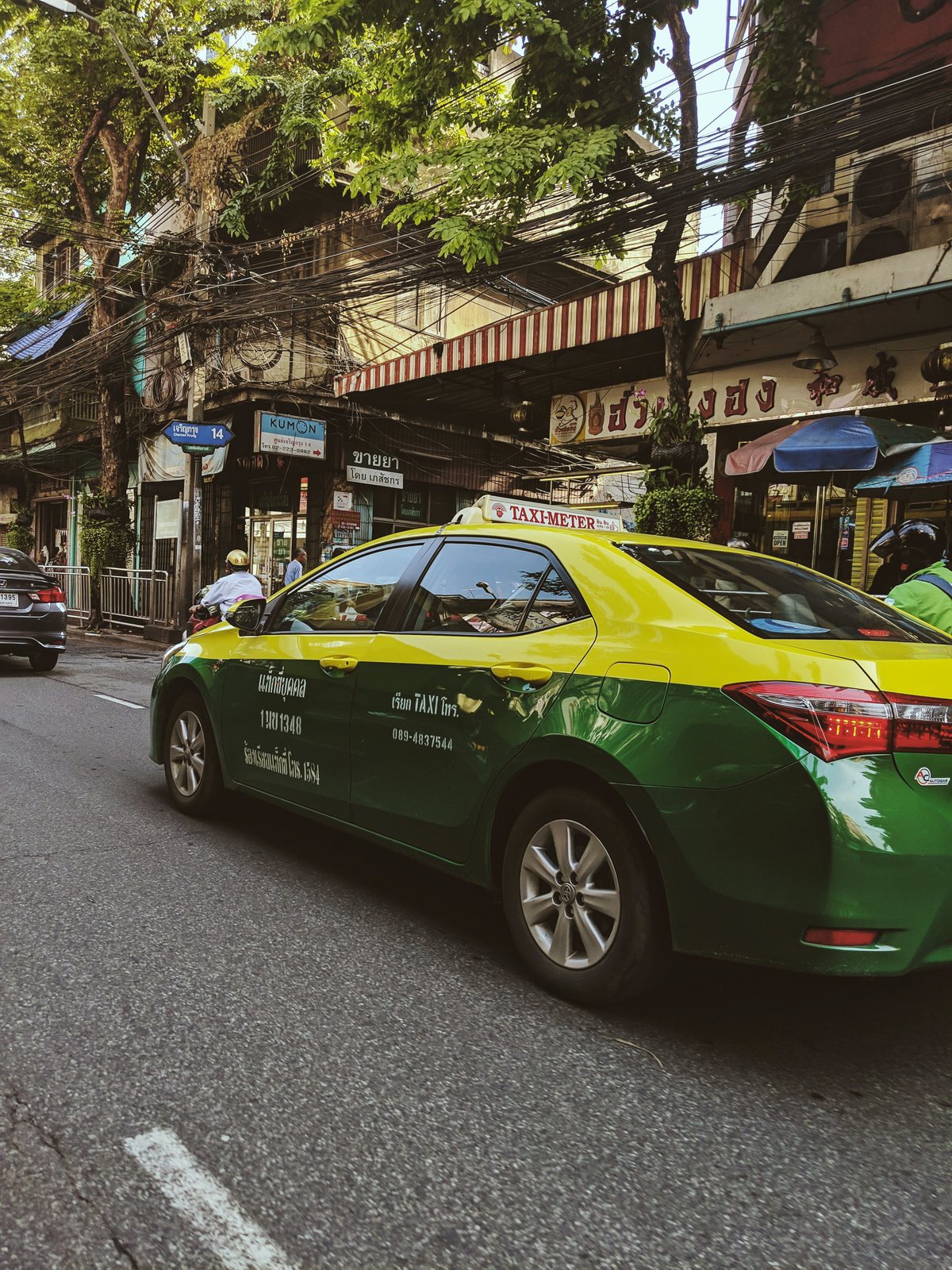 A line of taxis or a songthaew pickup truck in a Thai town