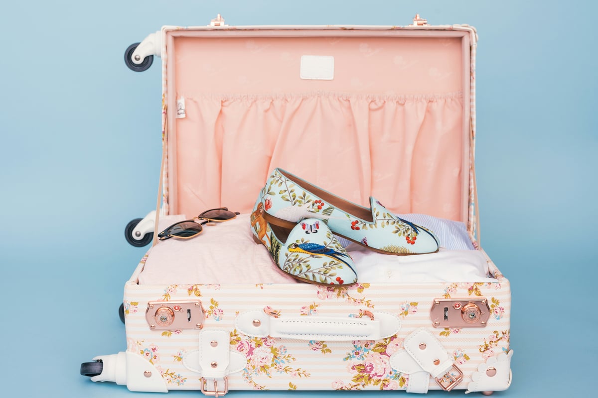 An open suitcase with light tropical travel clothing and essentials