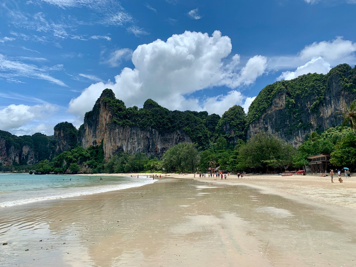 A quiet longtail-dotted beach with clear shallow water, fewer crowds