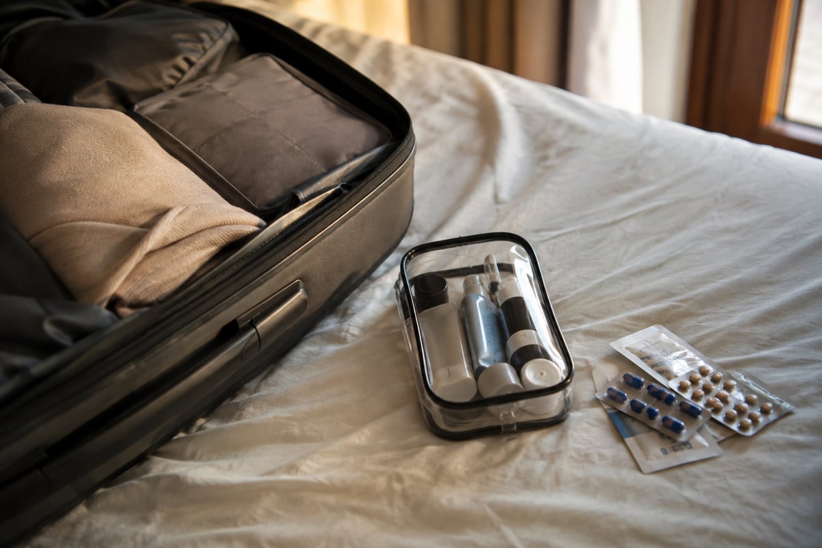 an open suitcase corner with a small clear toiletry bag and packaged medication, tidy, anonymous, no faces, no labels legible