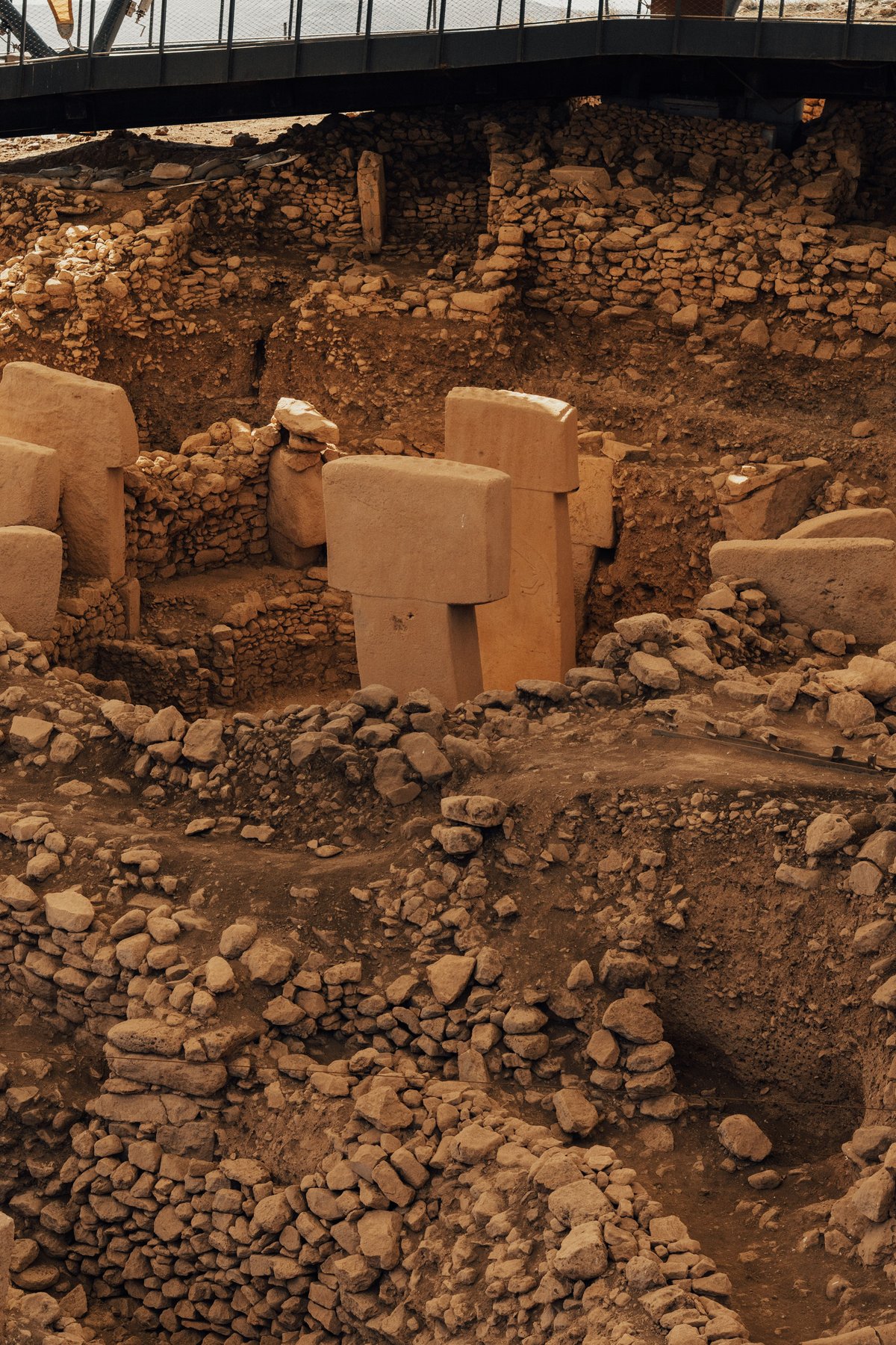 The carved T-shaped megalithic pillars of Göbeklitepe under their protective canopy, no recognizable faces