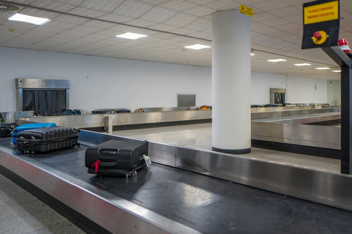 Suitcases circling on a baggage carousel in a bright airport arrivals hall