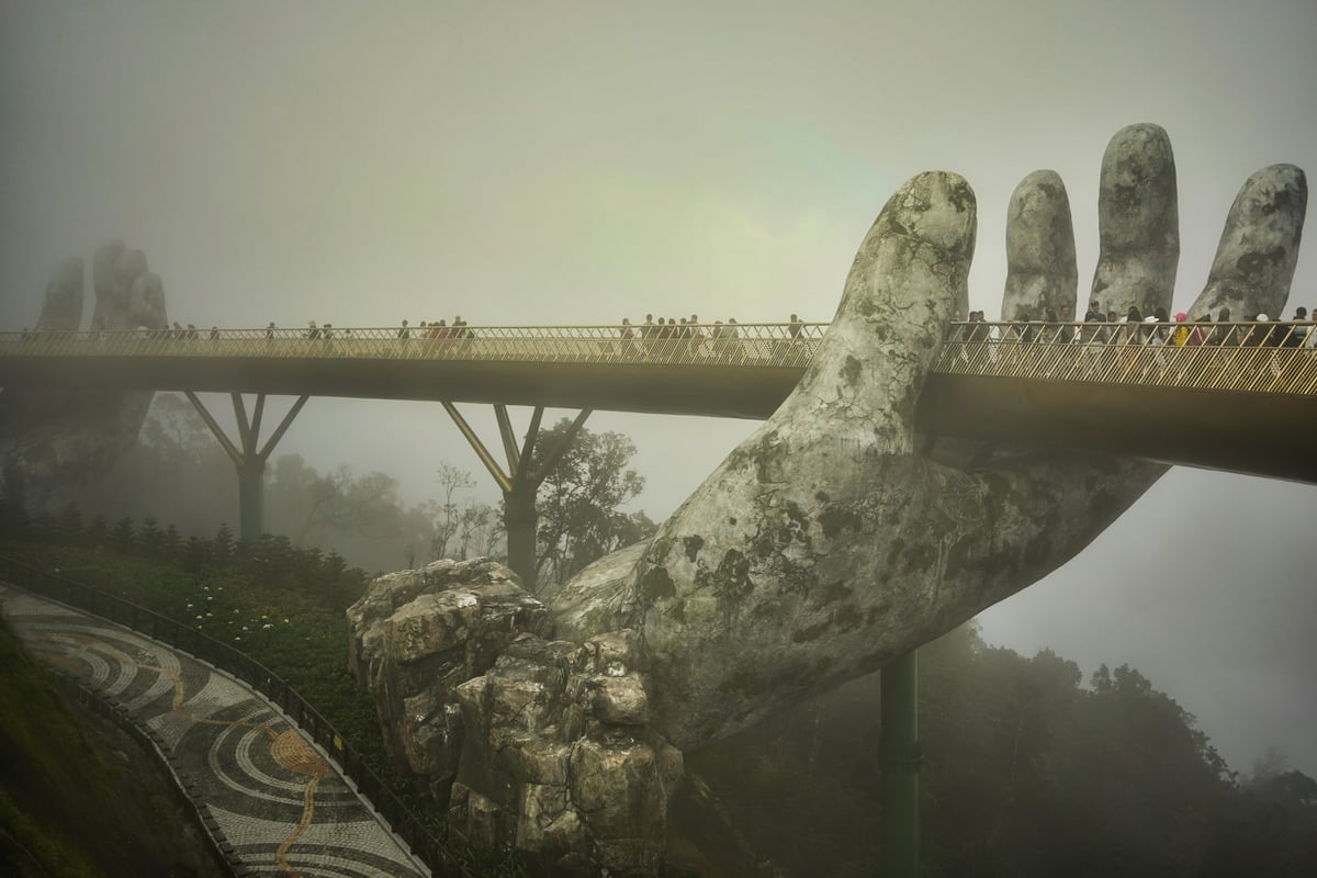 The Golden Bridge held up by two giant stone hands, with cloud closing in around it