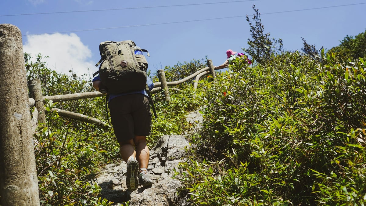 A trekker with a loaded pack climbing a hill path in the northern highlands
