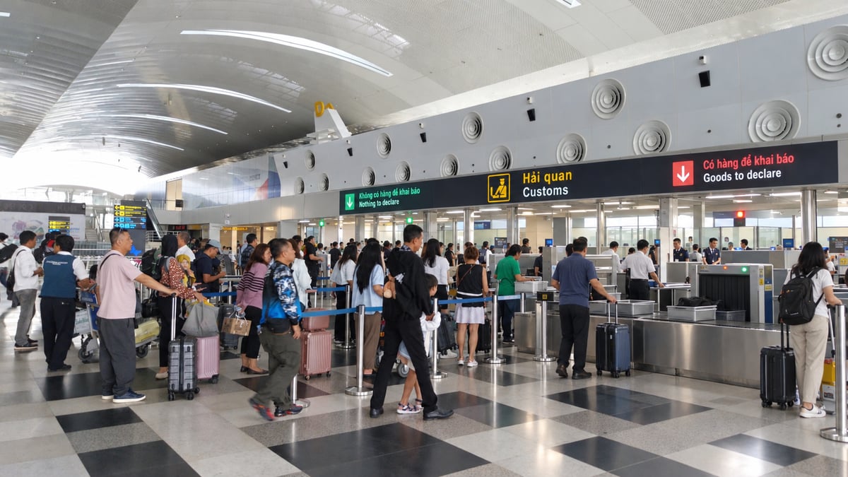 Travelers with suitcases walking through the arrivals and customs hall of a Vietnamese airport toward the exit channels