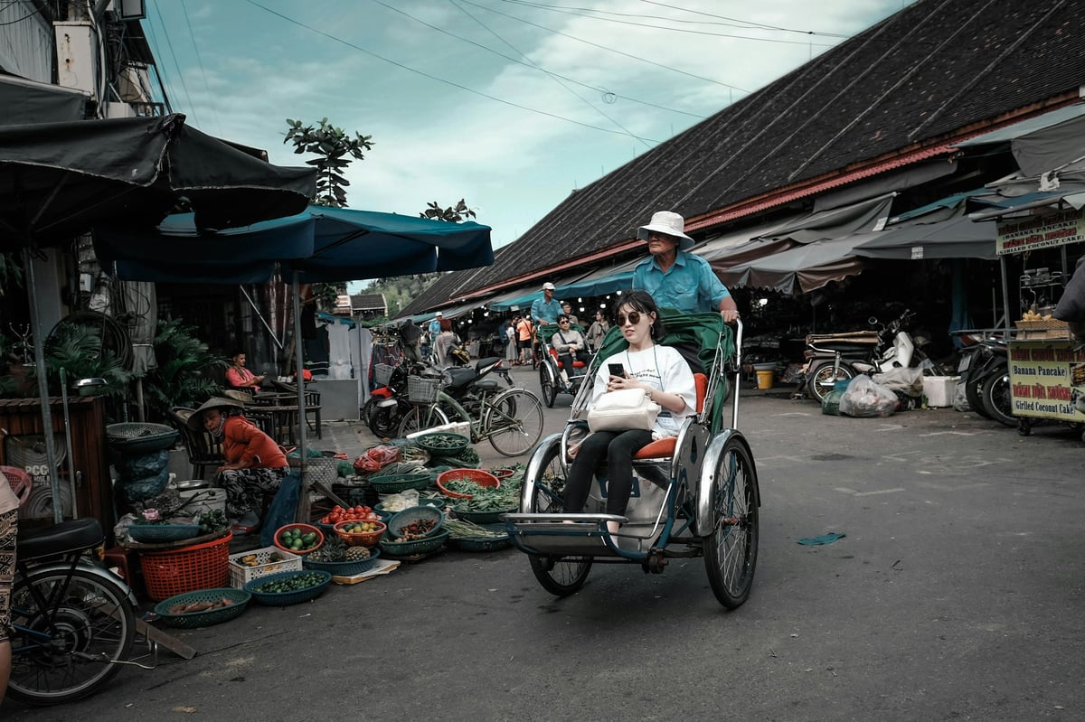 Motorbikes parked along a Vietnamese street with a cyclo passing