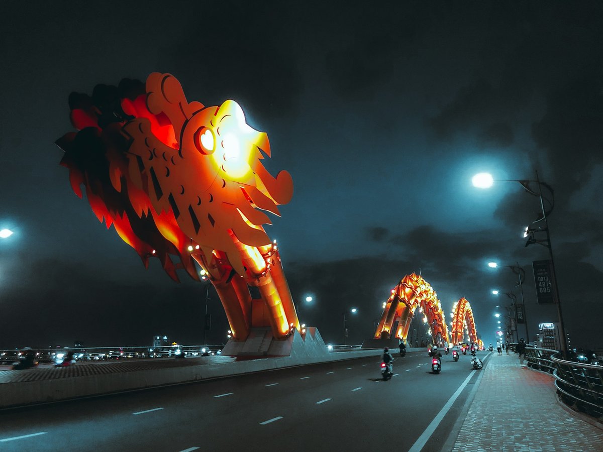 The Dragon Bridge in Da Nang lit at night, breathing fire over the road