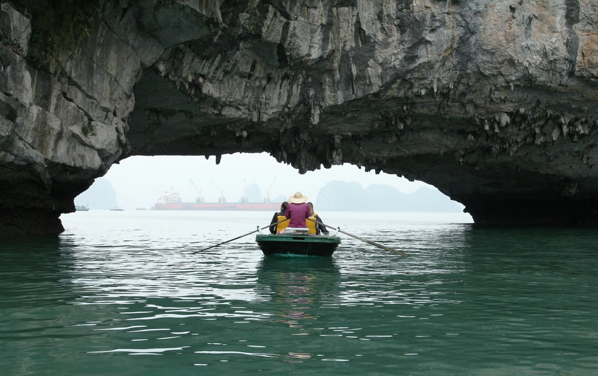 A small rowed boat passing through a limestone arch in northern Vietnam