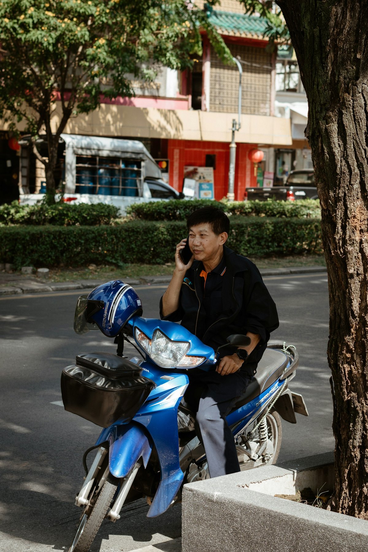 A man taking a call at the roadside beside a parked motorbike