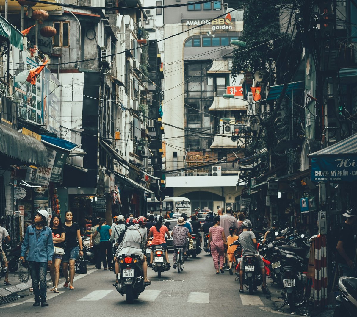 A dense Hanoi street with tangled overhead cables and passing motorbikes