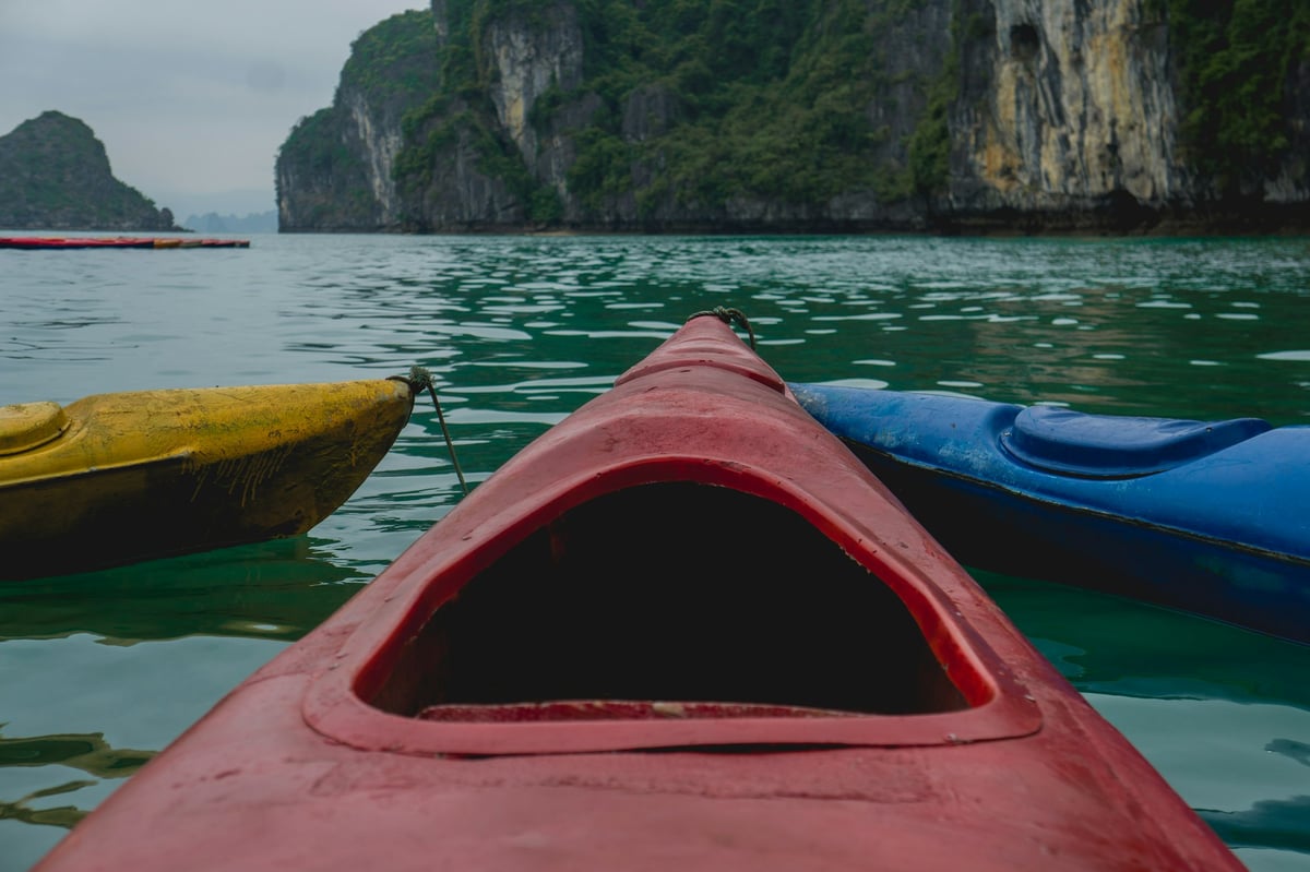 Kayak bows on the green water of Ha Long Bay beneath limestone cliffs
