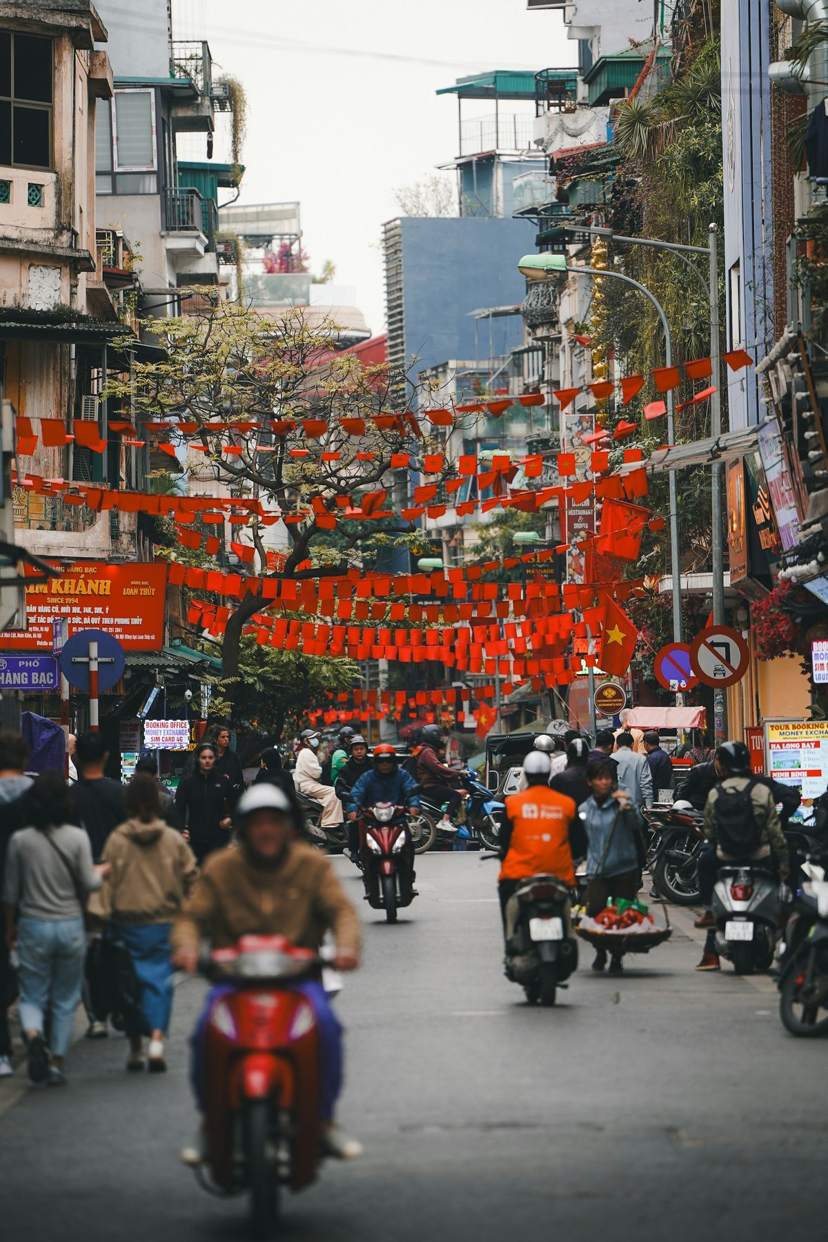 A Hanoi street hung with red banners and lanterns above the shopfronts