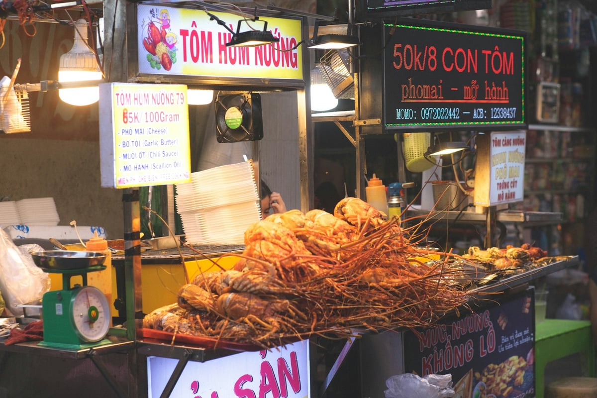A night food stall with grilled seafood and prices chalked up behind it